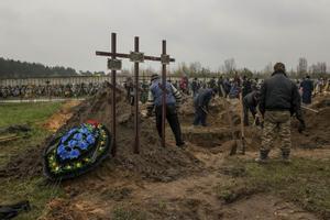 Varias personas entierran un cuerpo en el cementerio de Bucha (Ucrania) el 22 de abril de 2022. Alina aguarda nerviosa bajo una intensa lluvia a que un camión descargue decenas de cadáveres para que sean analizados en la morgue de Bucha. Esta joven de 24 años tiene que reconocer el cuerpo de su padre, del que no sabe nada desde que las tropas rusas entraron a esta castigada localidad y masacraron a su población. EFE/Miguel Gutiérrez