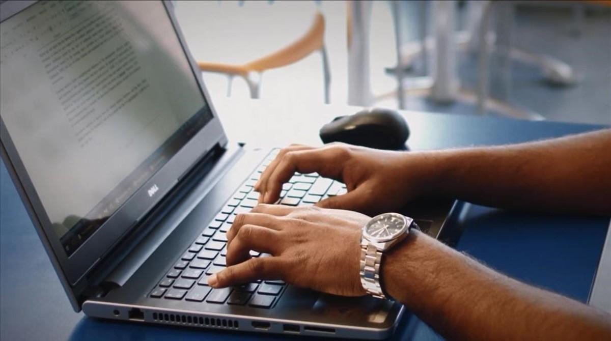 Un hombre teclea en un ordenador portátil. 