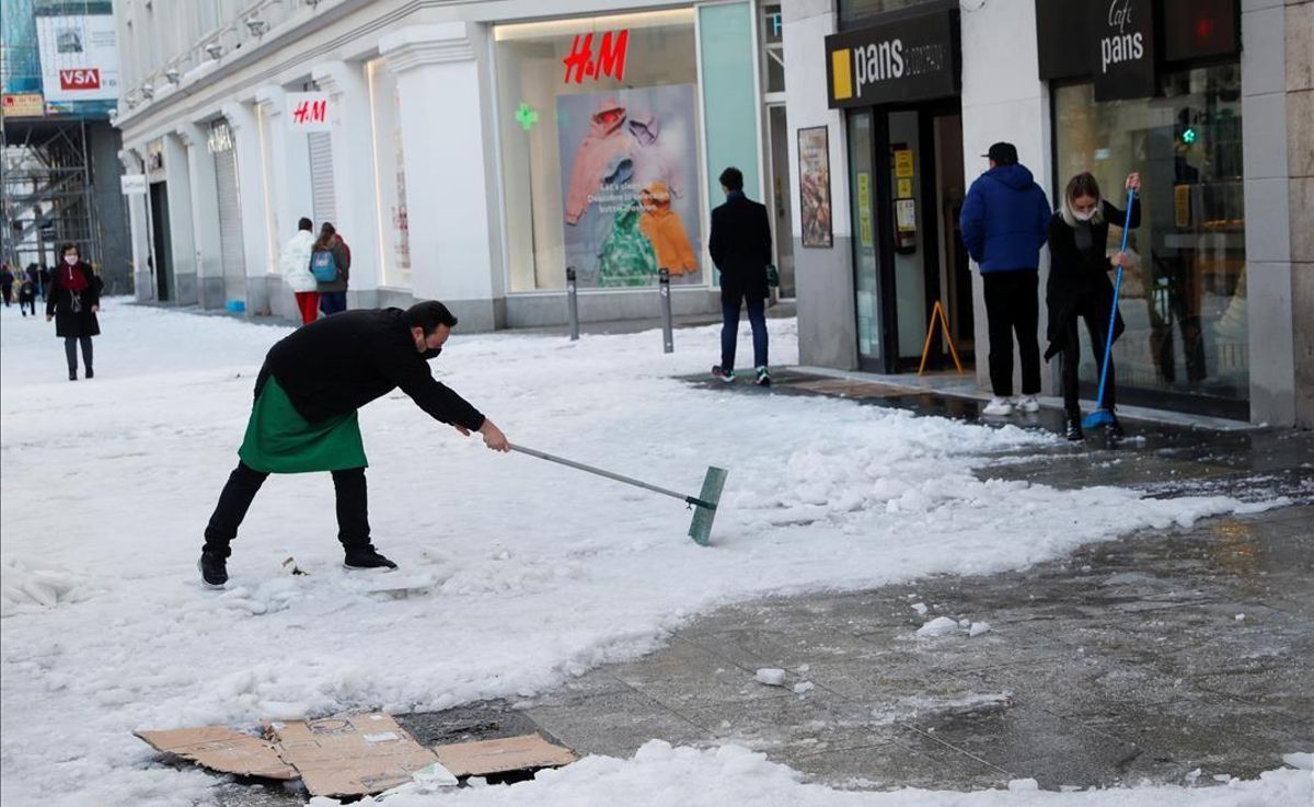 Un empleado de un comercio en la Gran Vía de Madrid retira la nieve de la acera, tras la nevada caída el fin de semana. Un empleado de un comercio en la Gran Vía de Madrid retira la nieve de la acera, tras la nevada caída el fin de semana.