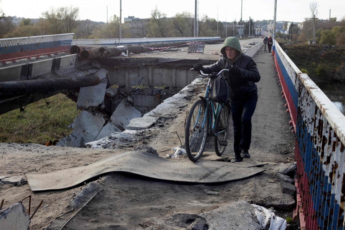 Un residente empuja su bicicleta por un puente destrozado cerca de Borivske, en la región de Járkov.