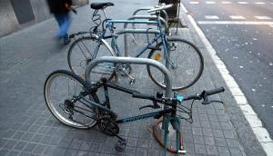 Cuadro de una bicicleta con una rueda robada en una estacionamiento en U en una calle de Barcelona.