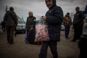 Un niño sonríe tras recibir una bolsa de piruletas, en el pequeño pueblo de Rozhivka, a unos 40 kilómetros al noreste de Kiev, Ucrania.