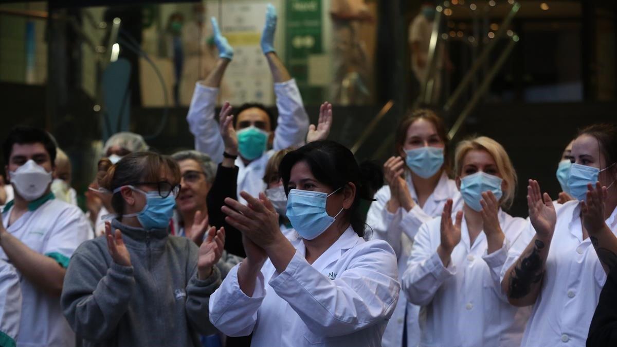 Sanitarios reciben el aplauso de la gente en la puerta del Hospital Clínic de Barcelona, ayer.