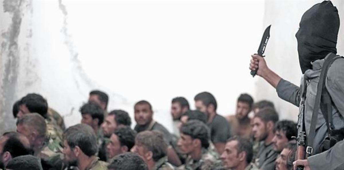 Combatiente del Estado Islámico junto a soldados sirios, tras la toma de una base cerca de Raqqa, una de los pocas batallas entre el EI y el régimen. Combatiente del Estado Islámico junto a soldados sirios, tras la toma de una base cerca de Raqqa, una de los pocas batallas entre el EI y el régimen.