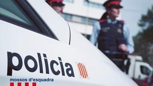 Una pareja de Mossos d’Esquadra, junto a un vehículo del cuerpo policial.