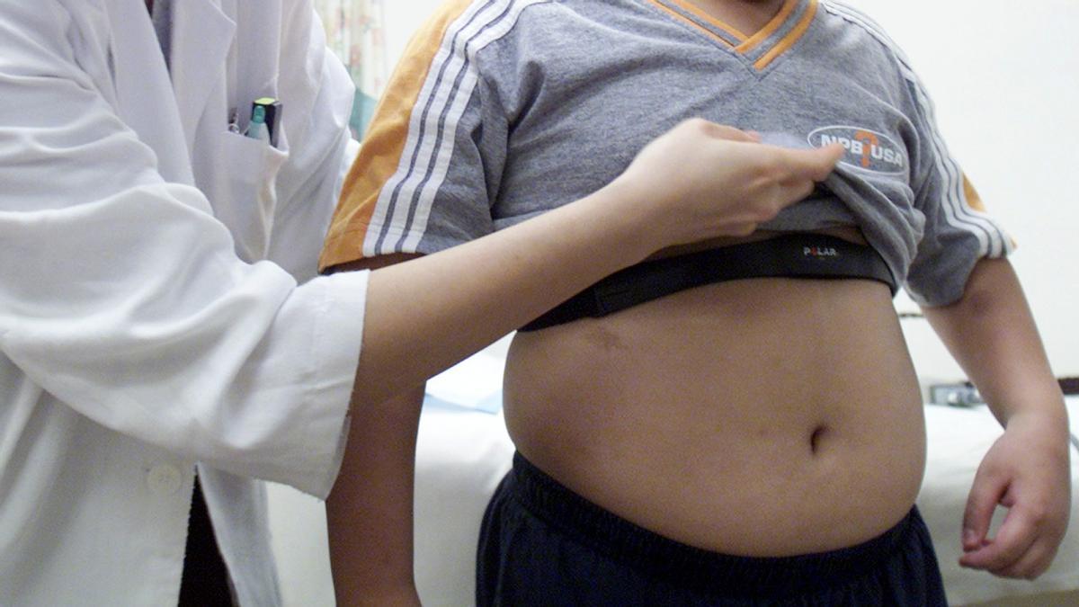 Una doctora muestra la barriga de un niño con sobrepeso.
