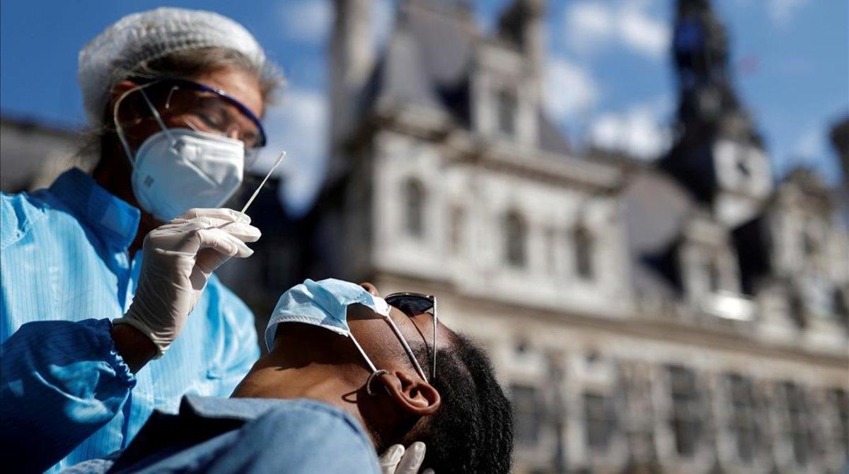 Un sanitario realiza una PCR frente al Ayuntamiento de París. 