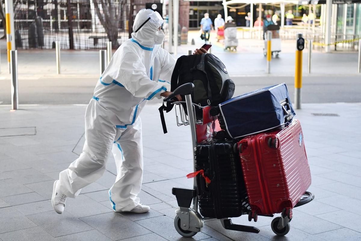 Un viajero viste un traje protector a su llegada al aeropuerto de Sidney, Australia.