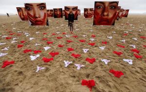 An activist poses for picture, between women’s underwear and photos from Brazilian photographer Marcio Freitas, during a protest by non-governmental organization (NGO) Rio de Paz (Rio of Peace) against rape and violence against women on Copacabana beach in Rio de Janeiro, Brazil, June 6, 2016. REUTERS/Sergio Moraes      EDITORIAL USE ONLY.     TPX IMAGES OF THE DAY