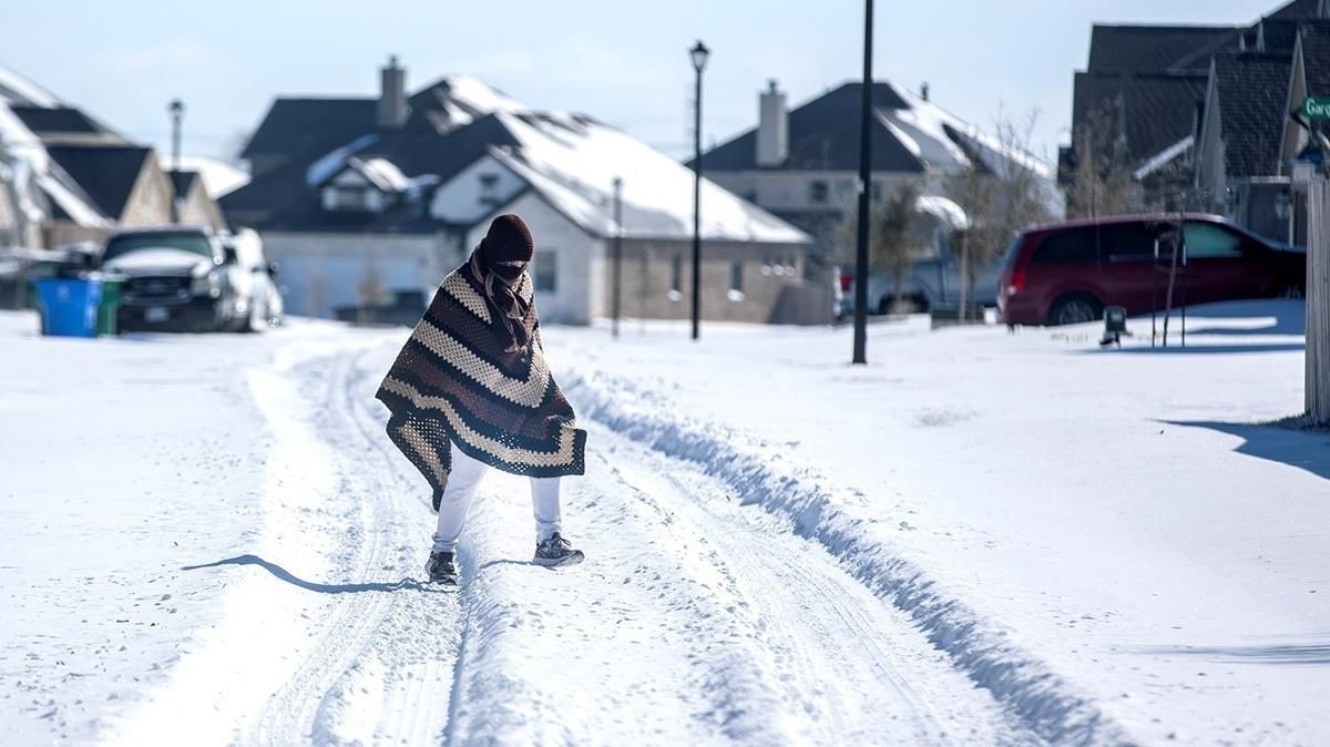 Una persona camina entre la nieve, cubierta con una manta, en Pflugerville, en Texas. Una persona camina entre la nieve, cubierta con una manta, en Pflugerville, en Texas.