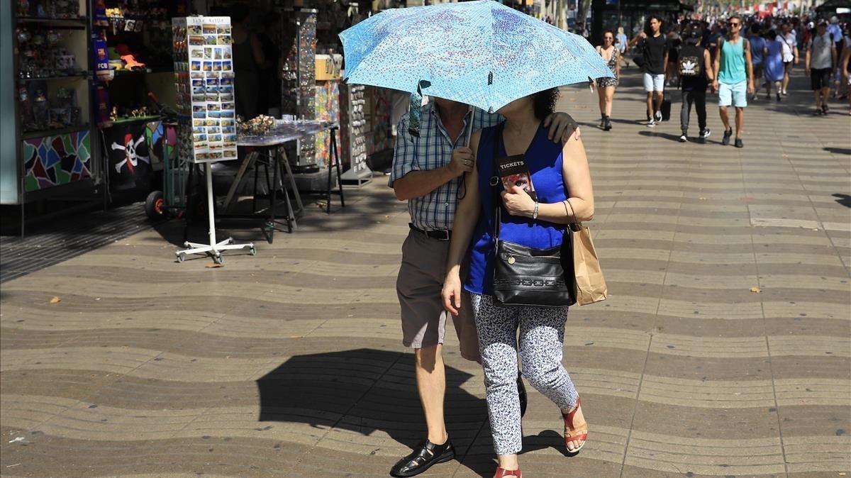 Una pareja se protege del sol con un paraguas en Barcelona.