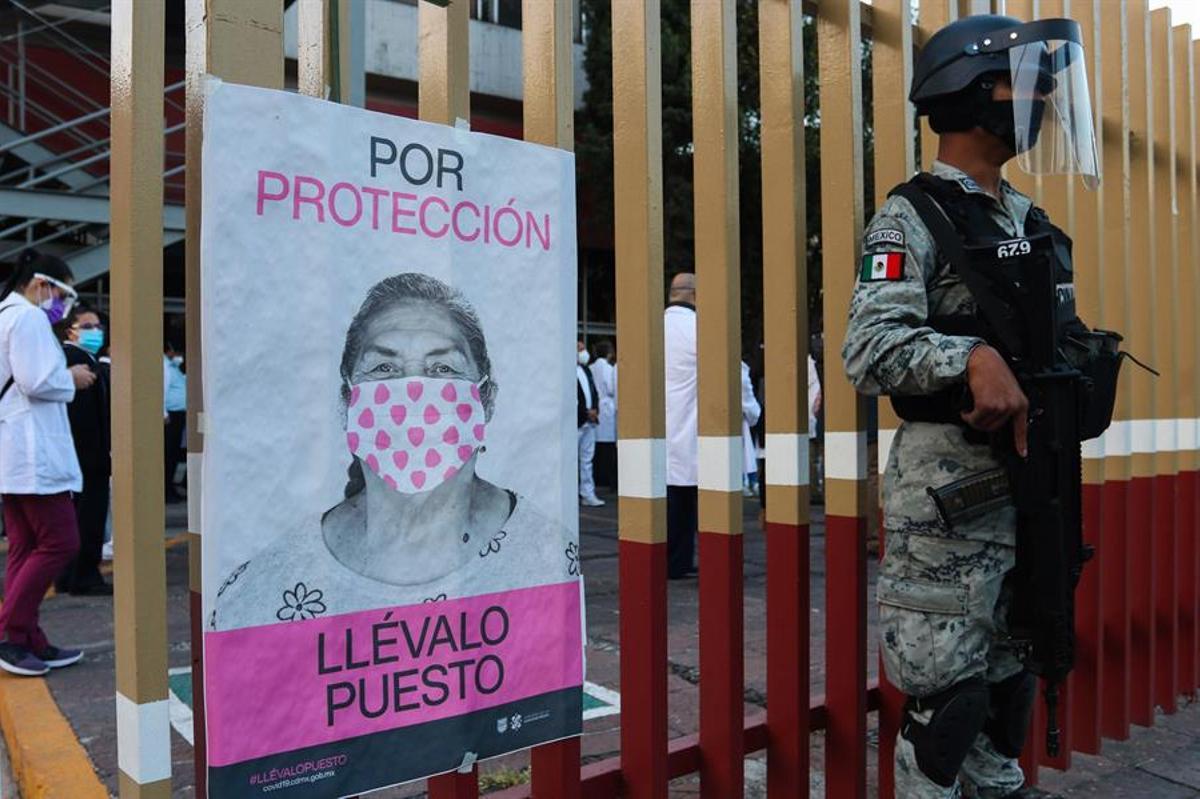 Soldados hacen guardia mientras personal médico hace fila para ser vacunado contra la covid-19 en el Hospital General, en Ciudad de México.