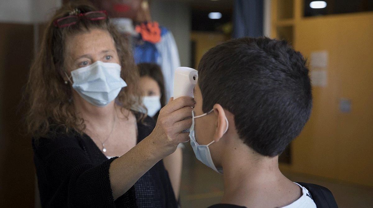 Una profesora del Institut Escola Antaviana de Barcelona comprueba la temperatura de un alumno, el pasado 15 de junio. Una profesora del Institut Escola Antaviana de Barcelona comprueba la temperatura de un alumno, el pasado 15 de junio.