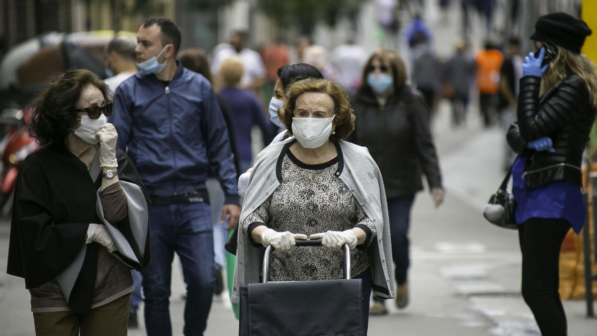 Gente paseando por una calle concurrida de Barcelona con mascarilla