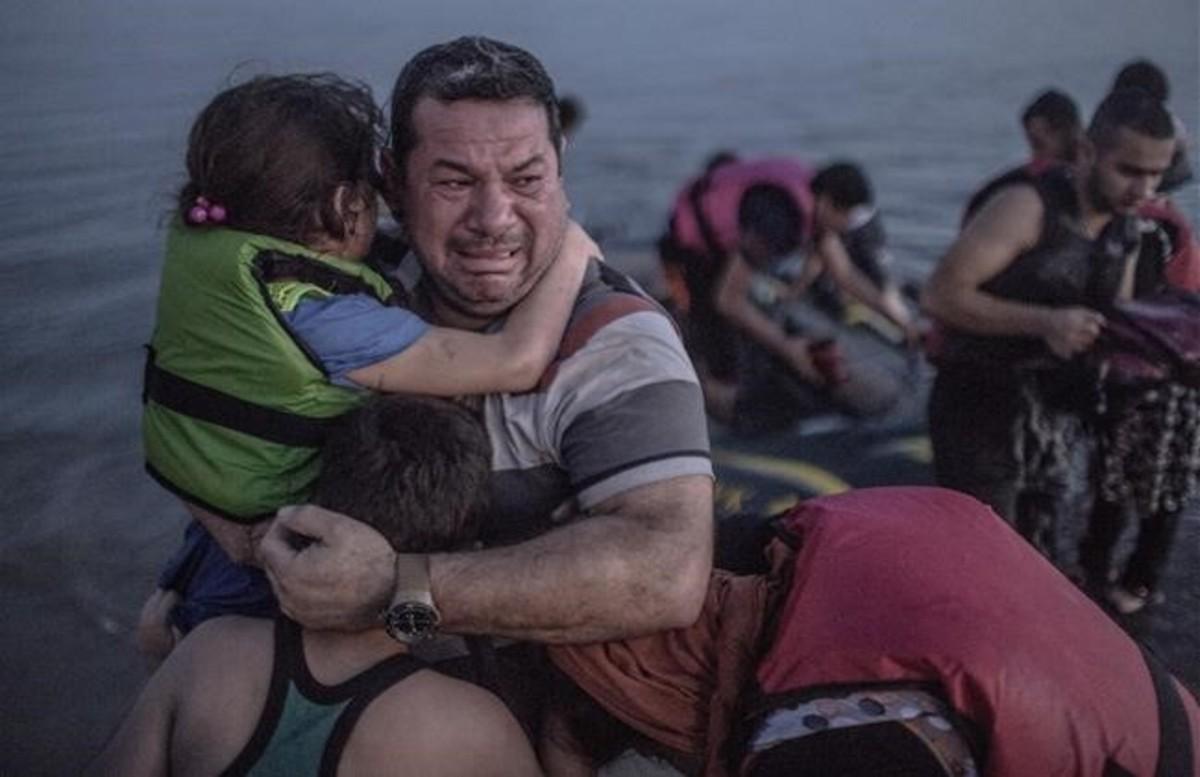 Un refugiado sirio de Deir Ezzor con su hija en brazos lloraba de emoción tras llegar en Agosto del 2015 con vida a la isla de Kos en Grecia después de una dura travesía a bordo de una barca hinchable. 