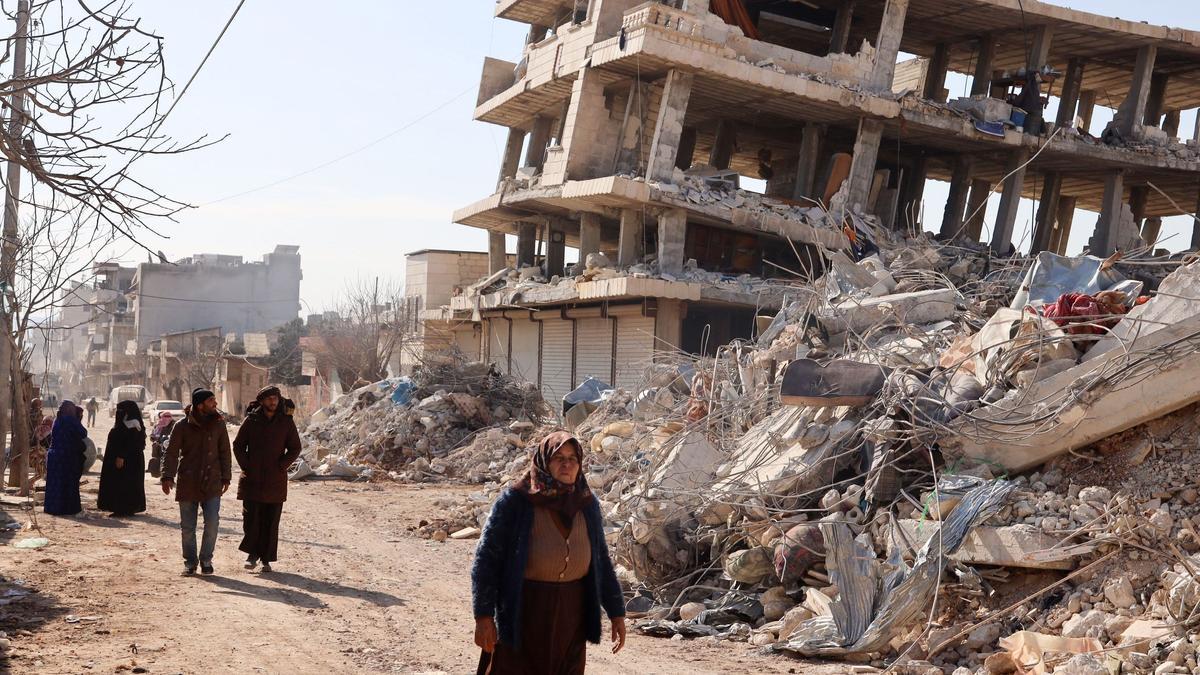 Los residentes caminan a lo largo de edificios destruidos en Jindayris, Siria, mientras continúan las operaciones de búsqueda y rescate días después que un terremoto mortal azotara Turquía y Siria.
