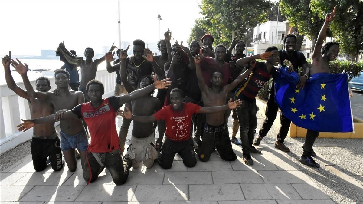Un grupo de los inmigrantes que ayer saltaron la valla en Ceuta posan con una bandera de la UE. Un grupo de los inmigrantes que ayer saltaron la valla en Ceuta posan con una bandera de la UE.