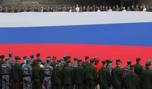 Soldados rusos sostienen una gigantesca bandera, durante el Día de la Bandera Nacional, este lunes.