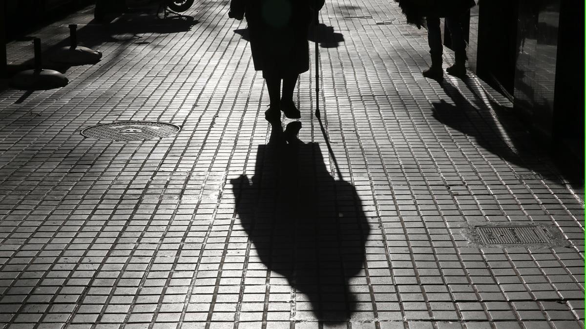Una anciana camina en solitario por Barcelona. 
