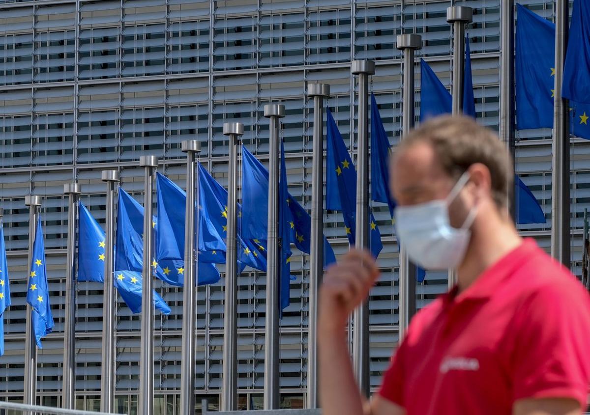 Brussels (Belgium), 25/05/2020.- A man wearing a face mask walks in front of the European Commission flags at the Berlaymont building headquarters in Brussels, Belgium, 25 May 2020. Countries around the world are gradually easing COVID-19 lockdown restrictions in an effort to restart the economy and help people in their daily routines. (Bélgica, Bruselas) EFE/EPA/OLIVIER HOSLET