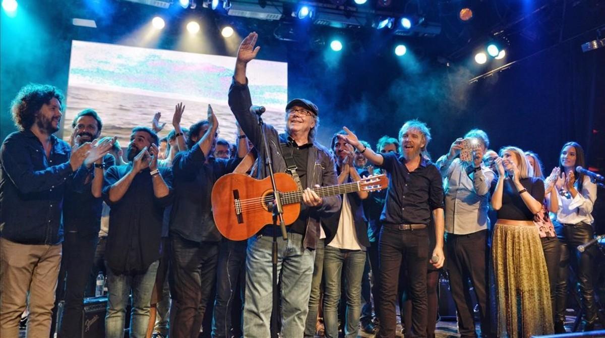 Serrat saluda al público asistente al concierto de Som Música Directa en Luz de Gas rodeado de otros cantantes y grupos.