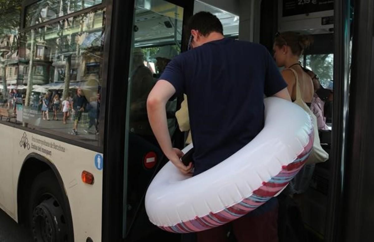 Un hombre con flotador incorporado trata de entrar en un bus lleno en el paseo de Joan de Borbó. Un hombre con flotador incorporado trata de entrar en un bus lleno en el paseo de Joan de Borbó.