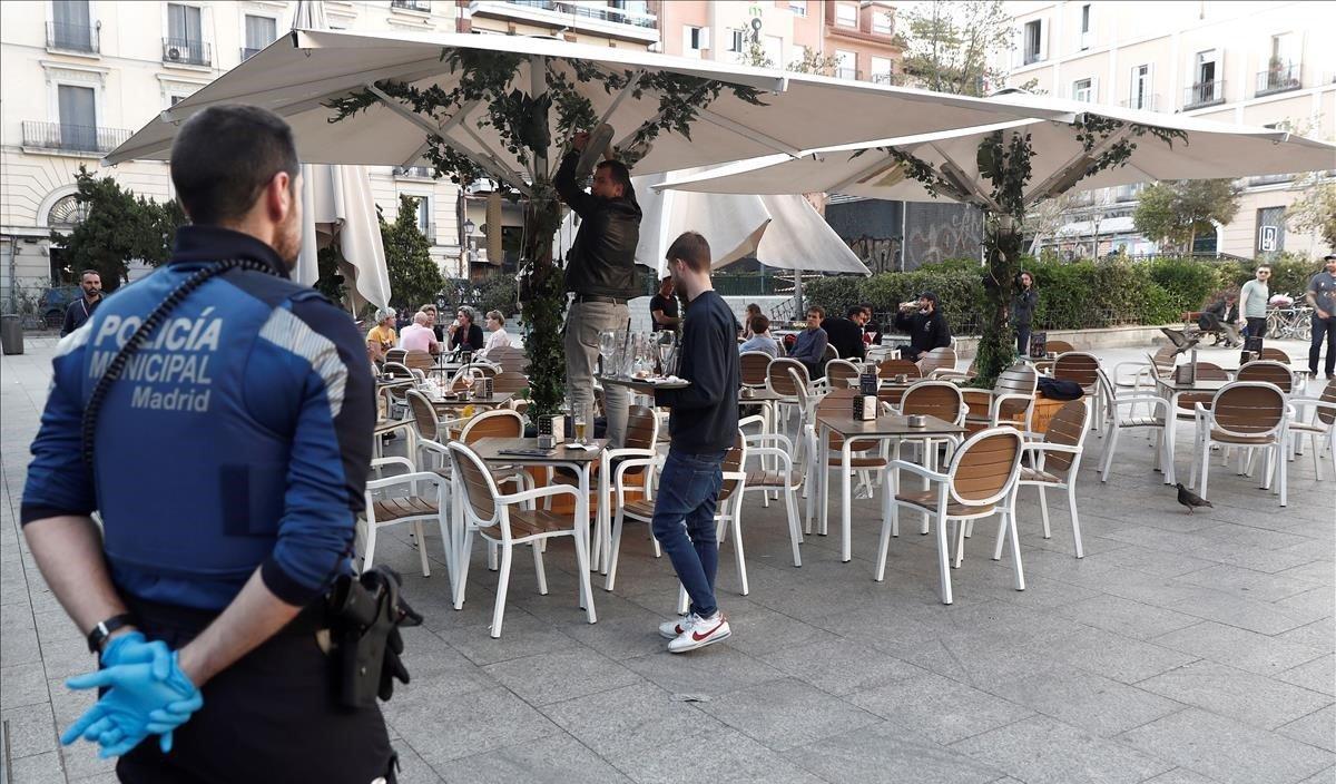 Un policía municipal de Madrid observa el cierre y recogida de una terraza.