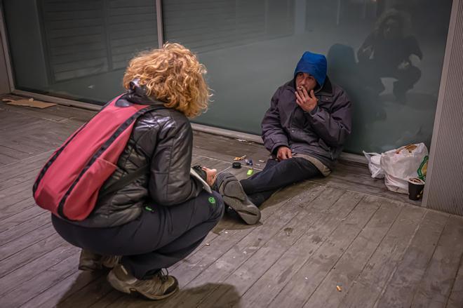 Una trabajadora social habla con un sin techo en Barcelona en enero, cuando se ofrecen lugares para dormir si el frío arrecia.