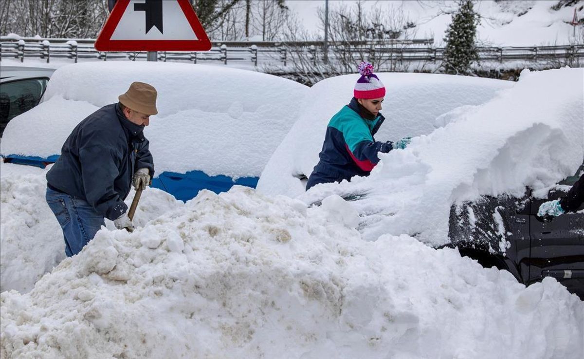 Unos vecinos quitan nieve de sus coches en el pueblo de Pajares. Unos vecinos quitan nieve de sus coches en el pueblo de Pajares.