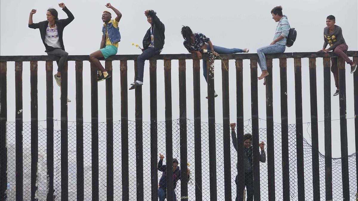 Miembros de la caravana de migrantes que cruzó México a pie hasta la frontera con Estados Unidos trepan el muro fronterizo que separa ambos países el pasado 29 de abril del 2018. 