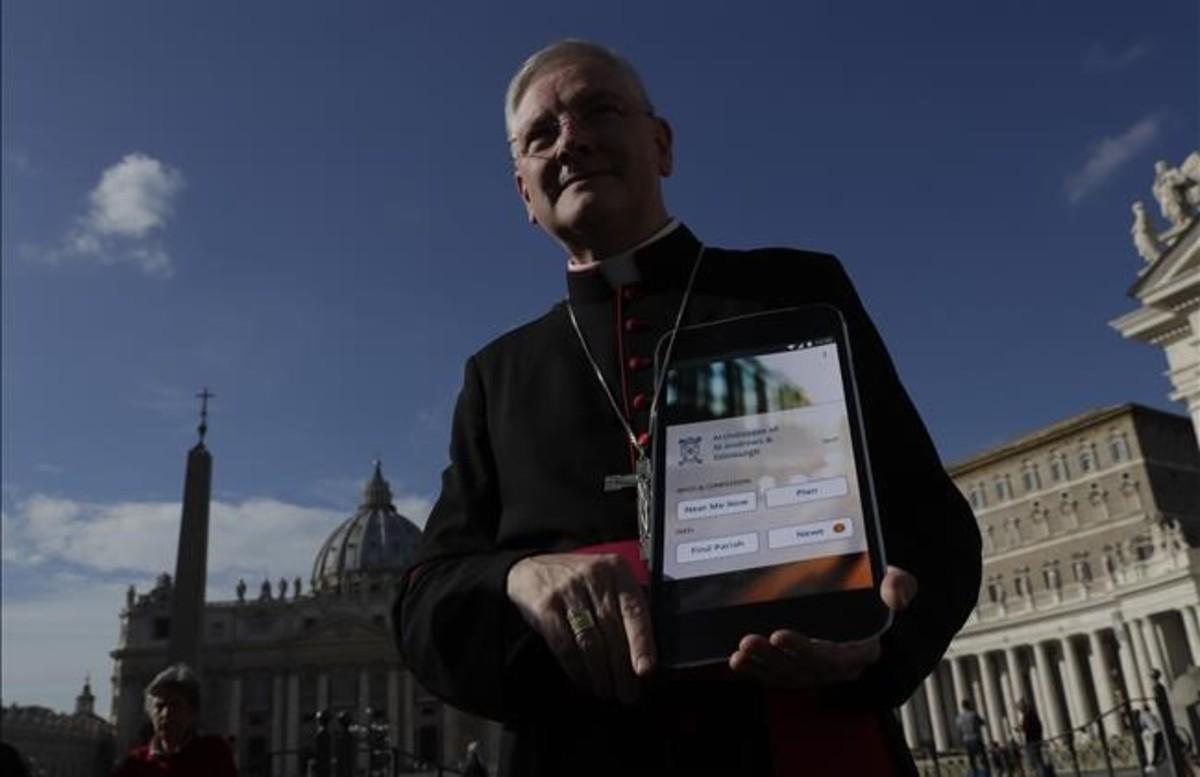 El arzobispo Leo Cushley sostiene un cartel de la futura Catholic App, en la plaza de San Pedro del Vaticano, el 22 de noviembre. 