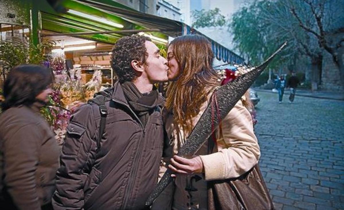 Una pareja se besa ante un puesto de flores de la calle de Santa Anna de Barcelona.