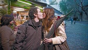 Una pareja se besa ante un puesto de flores de la calle de Santa Anna de Barcelona.