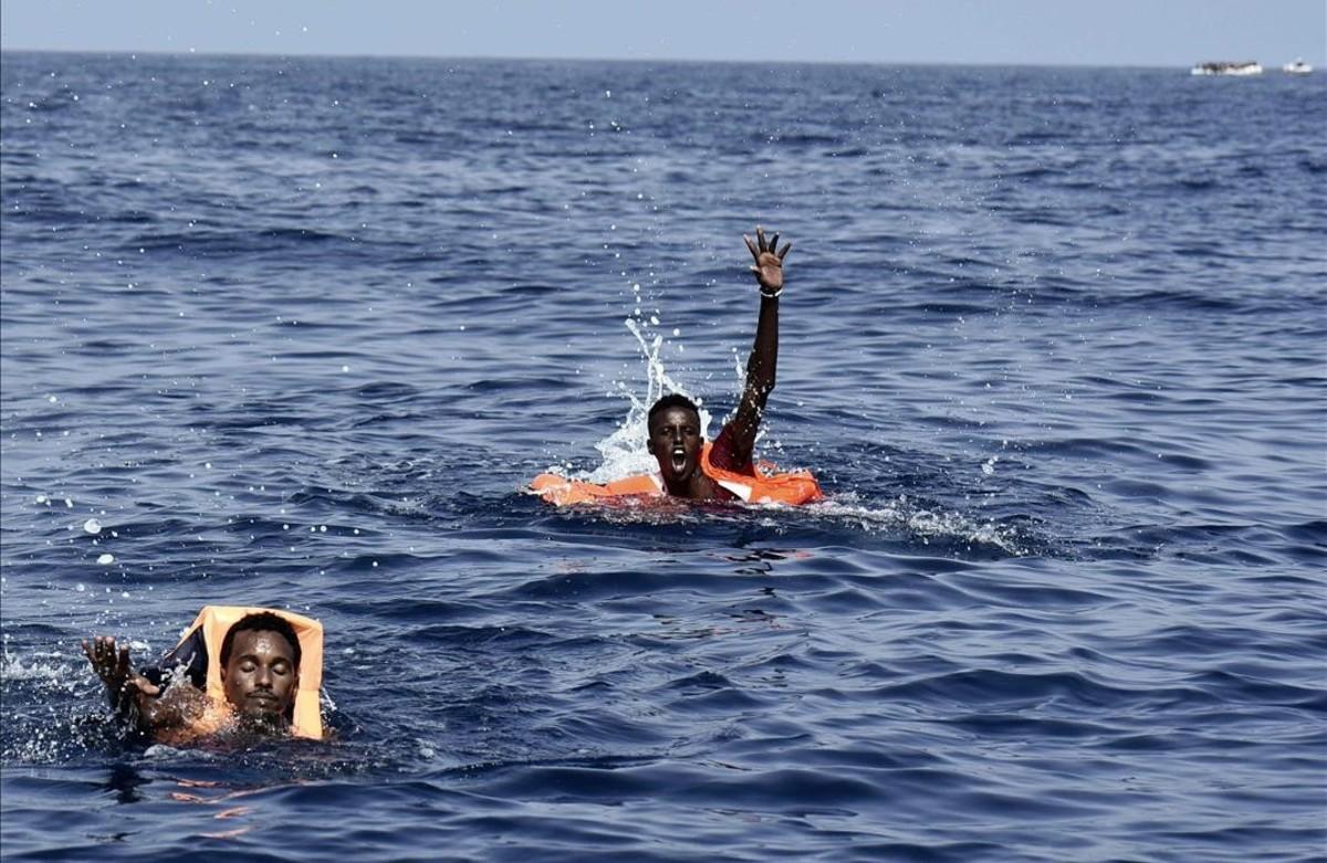 Dos migrantes a punto de ser rescatados por miembros de Proactiva Open Arms en aguas del Mediterráneo.