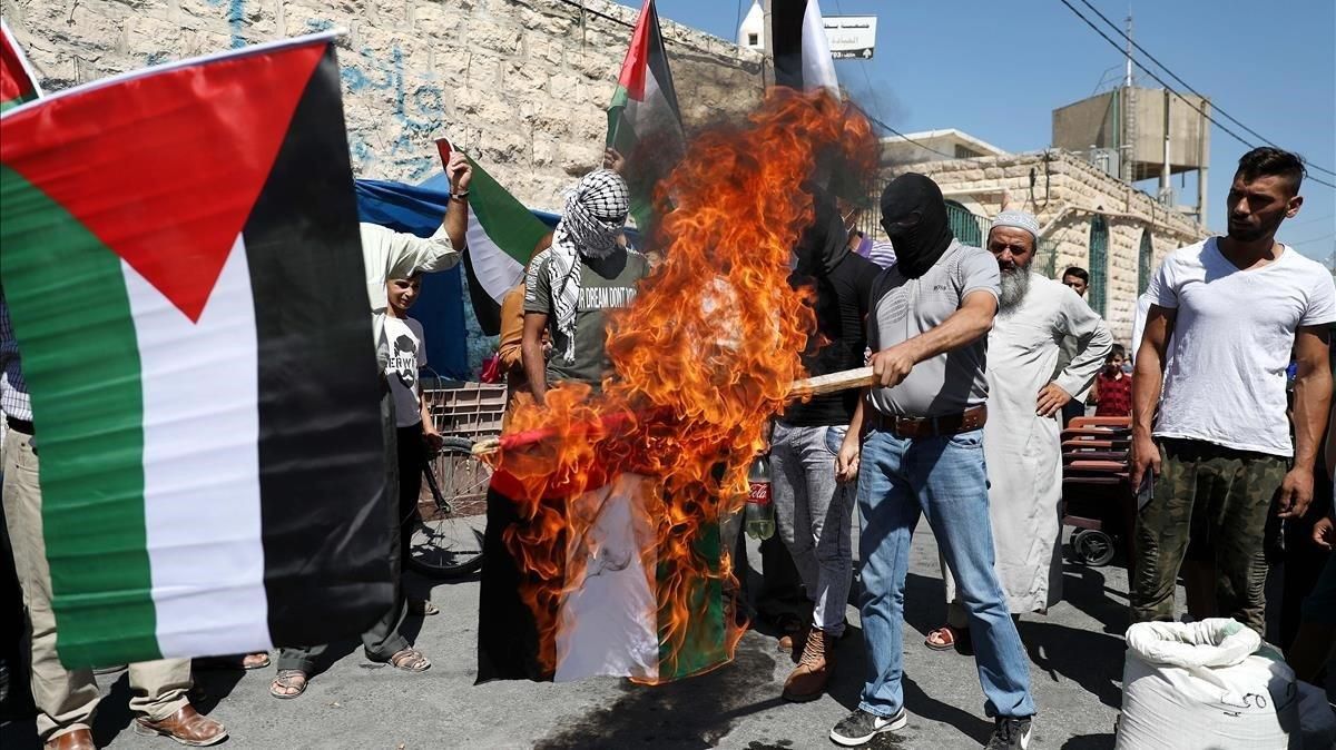 Manifestantes palestinos queman la bandera de EAU en la ciudad de Yata cerca de Hebrón. Manifestantes palestinos queman la bandera de EAU en la ciudad de Yata cerca de Hebrón.