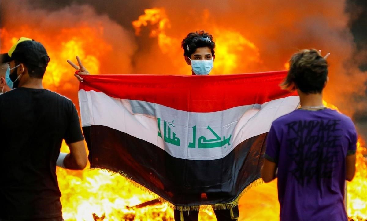 Un manifestante sostiene la bandera iraquí durante unas protestas contra el Gobierno del país, en Bagdad. Un manifestante sostiene la bandera iraquí durante unas protestas contra el Gobierno del país, en Bagdad.
