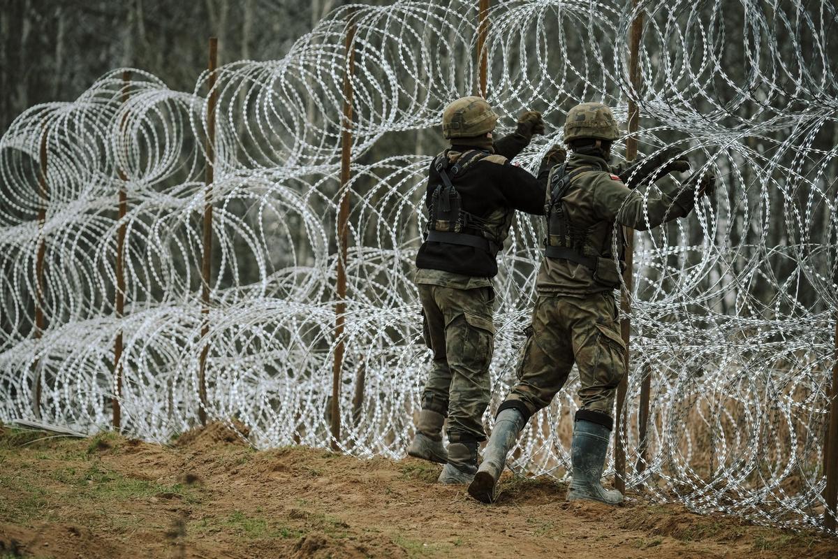 Soldados del ejército polaco arreglan bobinas de alambre de púas en una valla a lo largo de la frontera polaca, con el enclave ruso de Kaliningrado, cerca de Zerdziny, Polonia