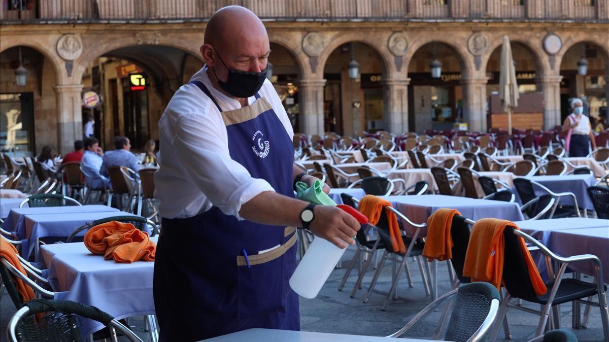 Un hostelero desinfecta las mesas de un bar de la Plaza Mayor de Salamanca, en una imagen de archivo