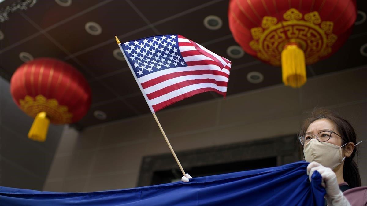 Un manifestante protesta con una bandera de EEUU frente al consulado de China en la ciudad de Houston.