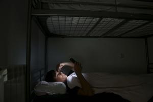 Un adolescente, en la cama y mirando el móvil, en su casa de Madrid.