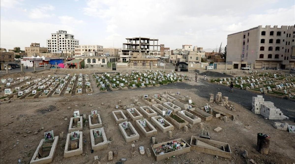 Yemenís caminan entre las tumbas con retratos de personas supuestamente asesinadas en combates en curso. 
