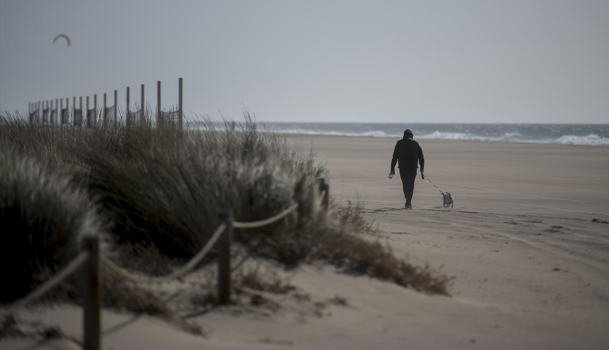 Un hombre pasea con su perro por la playa del Baixador de Castelldefels en marzo de 2023.