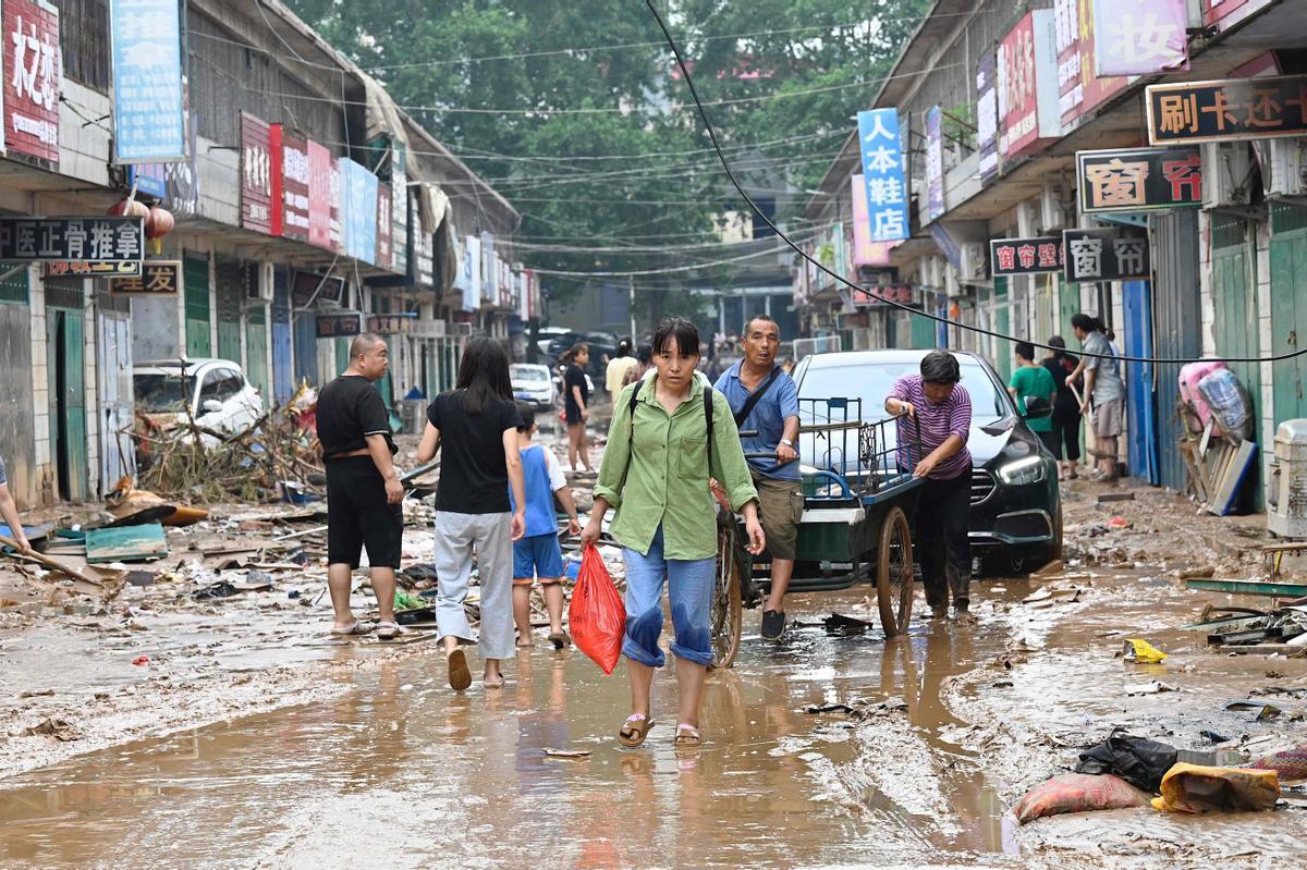 Varias personas se desplazan por el centro del condado de Gongyi, uno de los puntos más afectados por las inundaciones y tormentas extremas de estos días en China. 