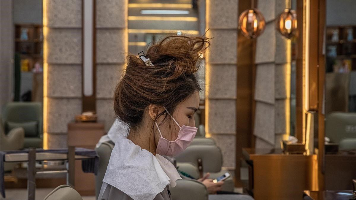Una mujer se protege con una máscara en su visita a una peluquería de la ciudad china de Wuhan. 