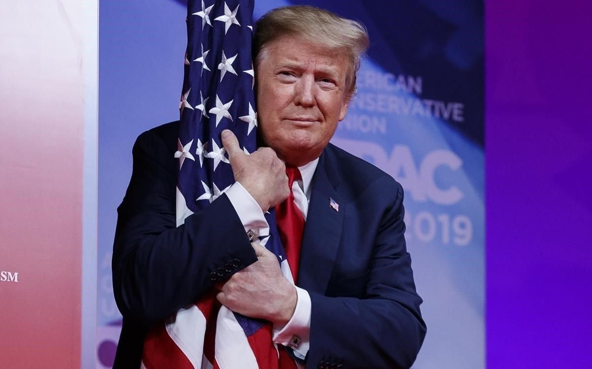 El presidente Donald Trump abraza la bandera de Estados Unidos en la Conferencia de Acción Política Conservadora. El presidente Donald Trump abraza la bandera de Estados Unidos en la Conferencia de Acción Política Conservadora.