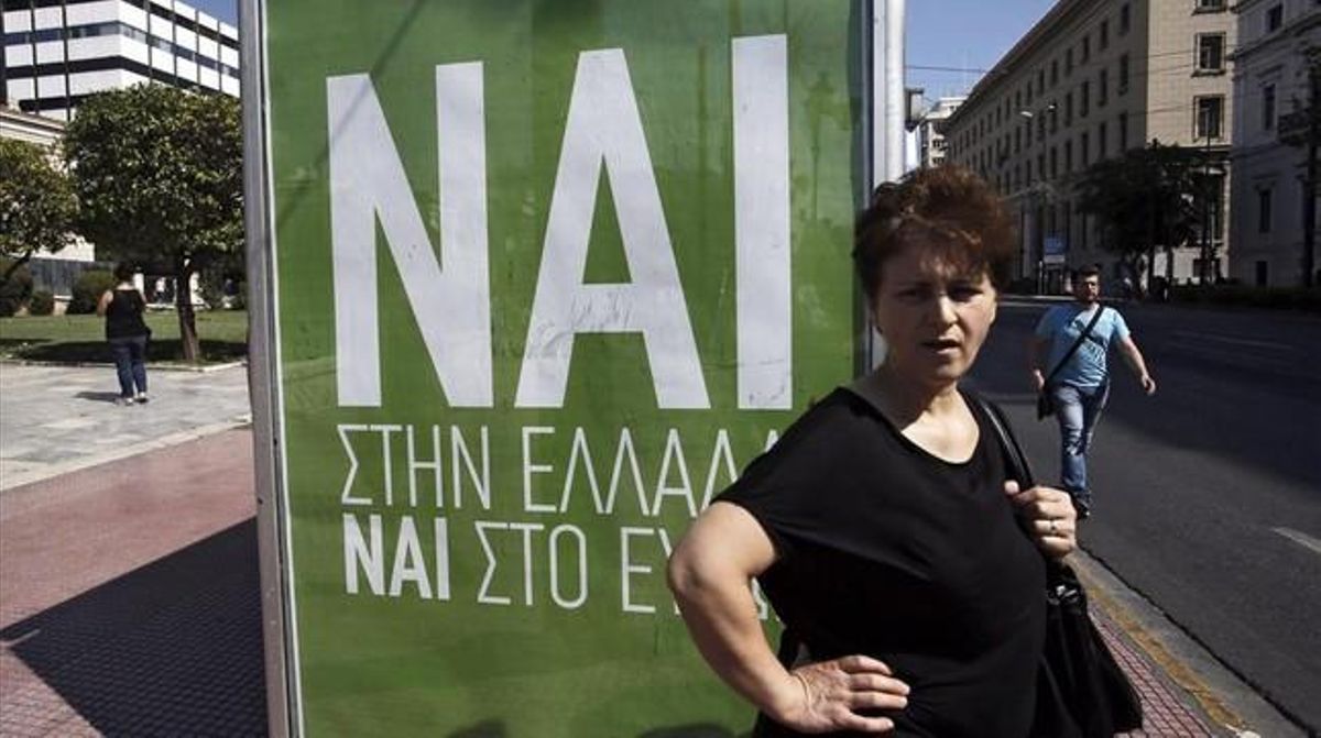 Una mujer espera el autobús junto a un cartel que pide el voto positivo en el referéndum, en el que se lee: Sí a Grecia, sí al euro. Una mujer espera el autobús junto a un cartel que pide el voto positivo en el referéndum, en el que se lee: Sí a Grecia, sí al euro.