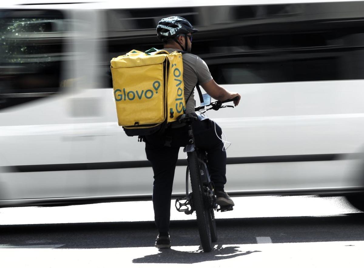 Un rider de la empresa de reparto de comida a domicilio Glovo, pasea por una calle de Madrid con su bicicleta en 2019.