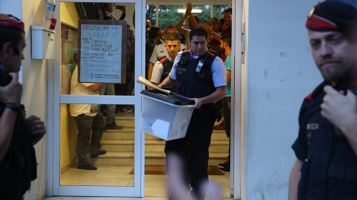 Un mosso se lleva una urna de un colegio durante el referéndum del 1-O. Un mosso se lleva una urna de un colegio durante el referéndum del 1-O.
