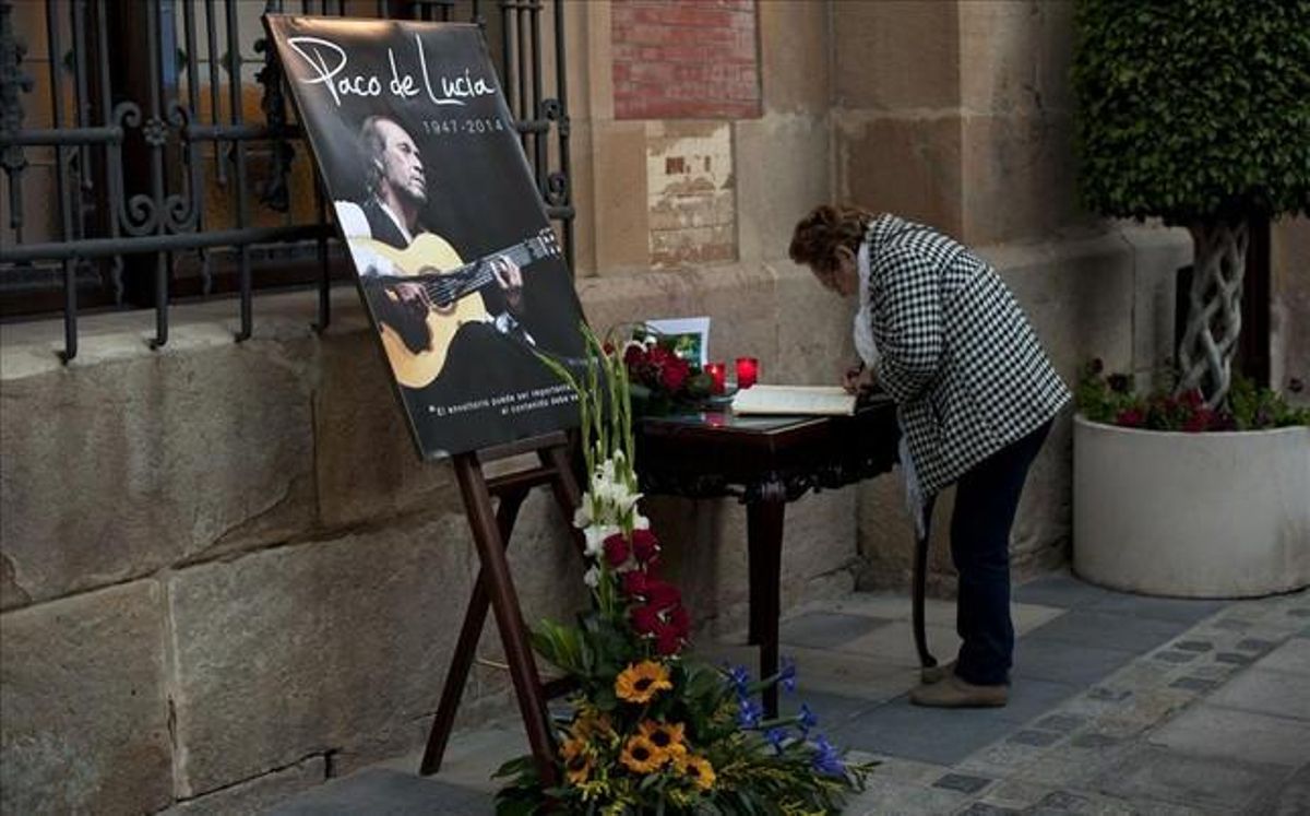 Una mujer firma en el libro de condolencias frente a un fotografía de Paco de Lucía en Algeciras Una mujer firma en el libro de condolencias frente a un fotografía de Paco de Lucía en Algeciras