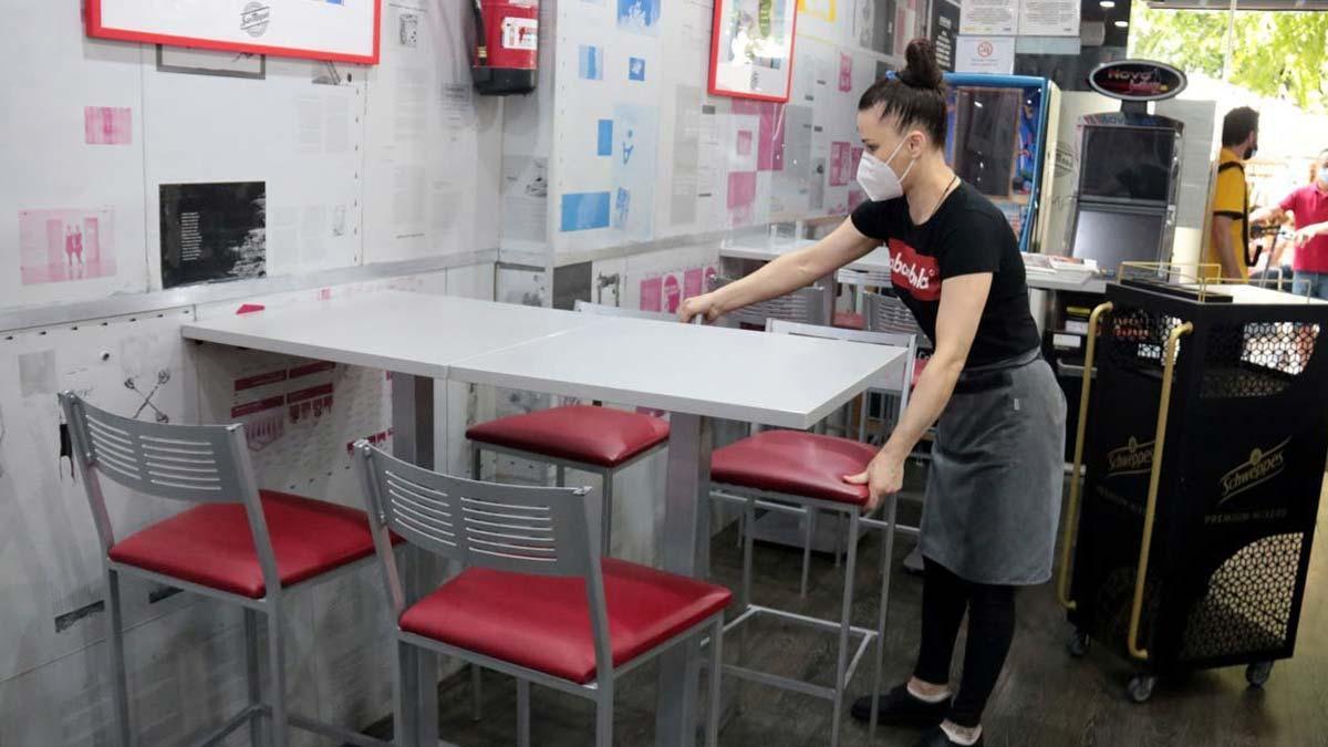 El IPC baja tres décimas en julio, hasta el -0,6%. En la foto, una empleada de un bar de Lleida prepara las mesas en el interior del local.